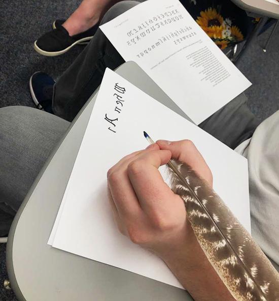 Student using a turkey feather quill to write